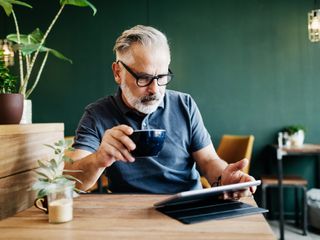 Man drinking a coffee while using a tablet