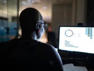 Woman working at night looking at graphs on a computer