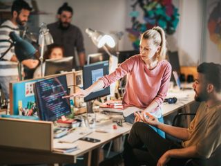 man and woman talking while looking at computer with data