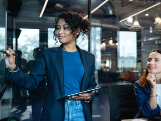 A female marketeer is on a presenting a market data on a digital display to make decision for new products launch with her team in a business office.