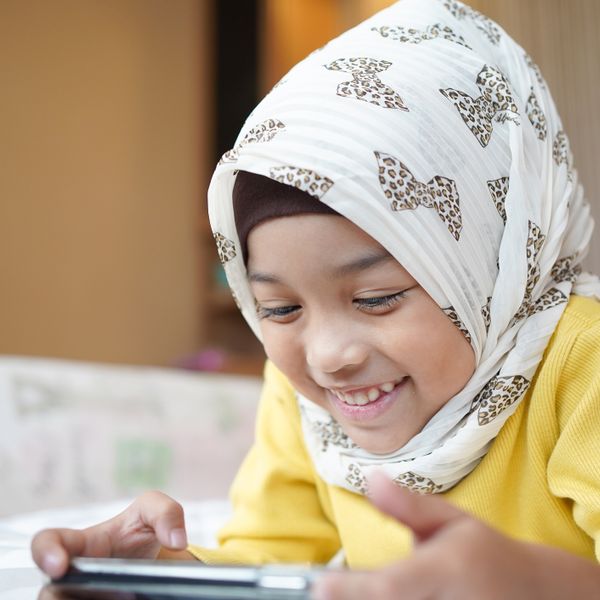 Asian Muslim child girl playing a smartphone at home