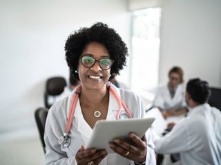 Female doctor using a digital tablet with doctor's meeting on background