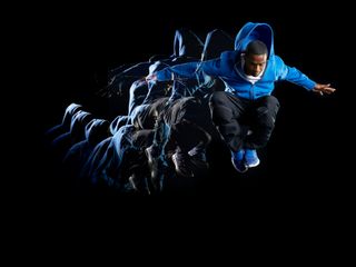 Man with blue jacket jumping in air with multiple strobe on a dark background