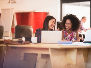 Two women smiling and working on a conference table